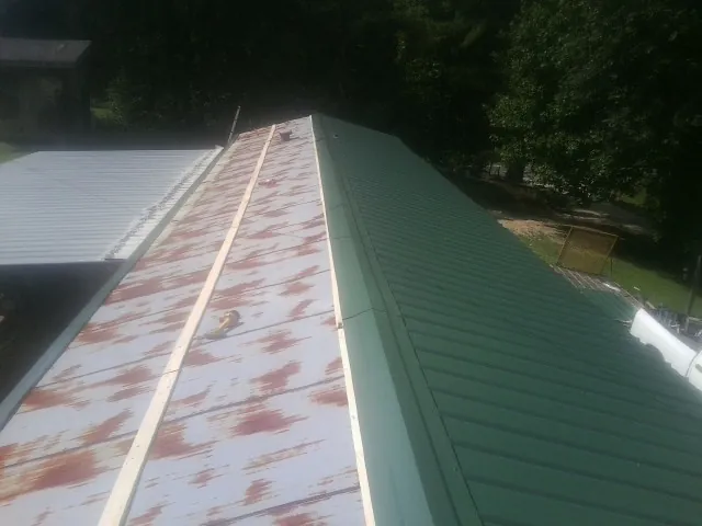 Old rusted panels beside newly installed green metal roofing — Wind Damage Roof Repair by Roofing Brothers in Keansburg
