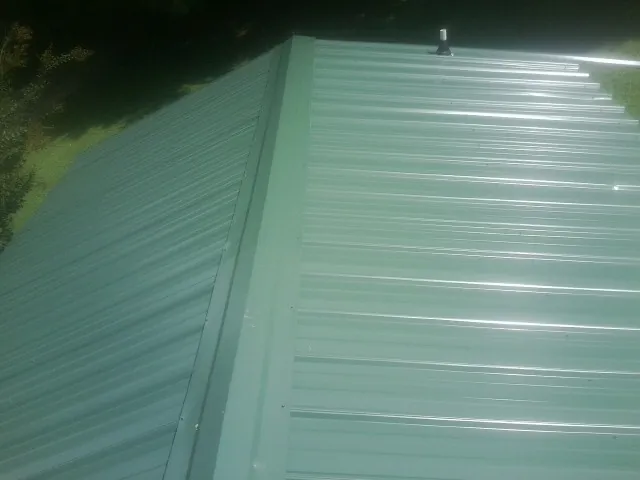 New green metal panels meeting at the ridge of a roof — Flat Roof Repair work by our crew in Keansburg