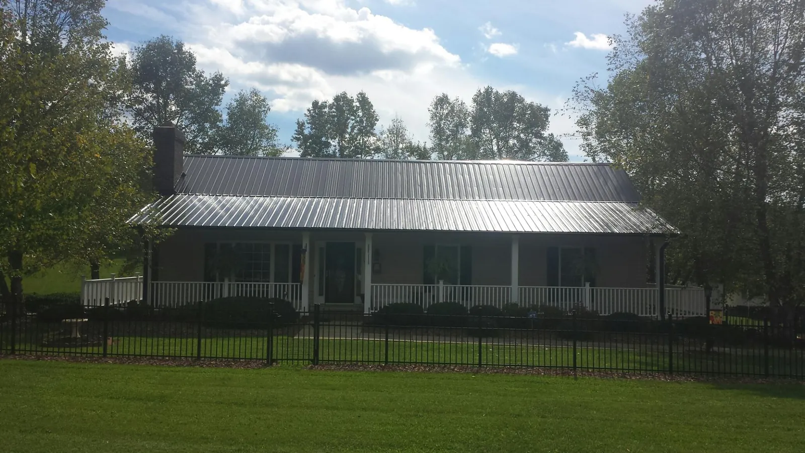 Gray metal roof on a brick ranch with a full width front porch — Gutter Guard Installation work by our crew in Keansburg