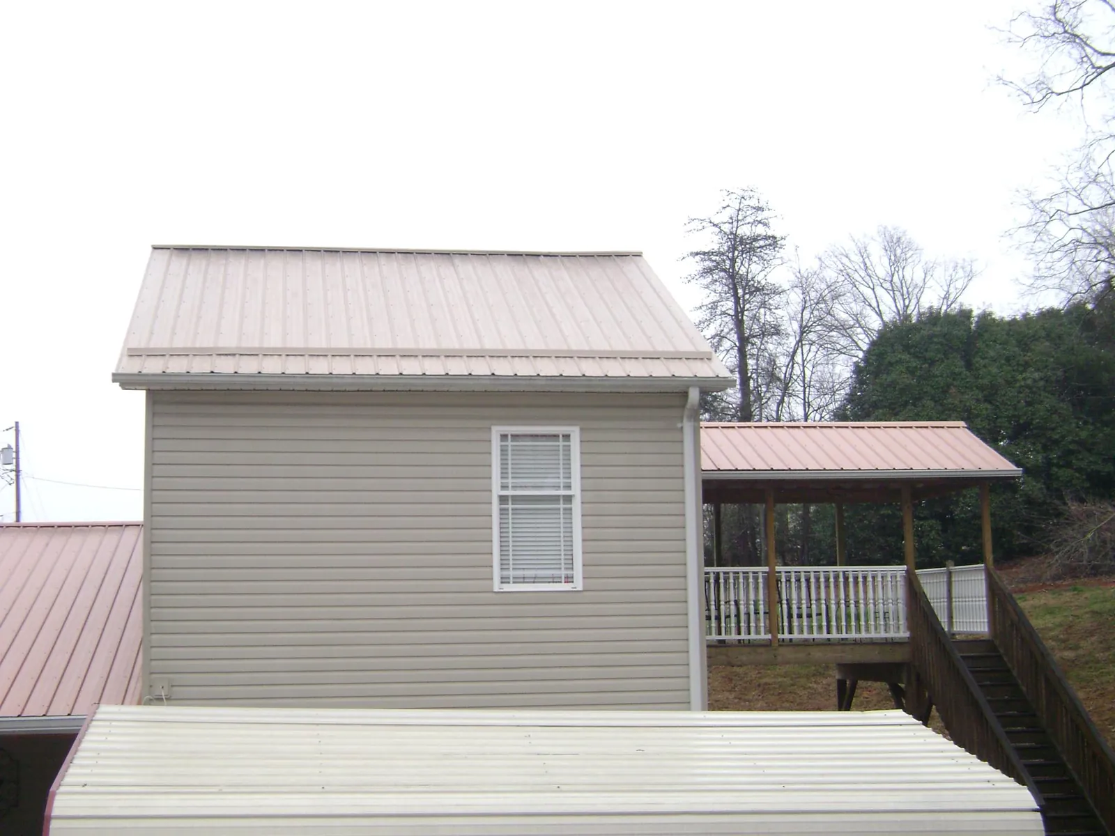Tan metal roofs on a two story addition and attached porch, from a Roof Replacement job in Keansburg